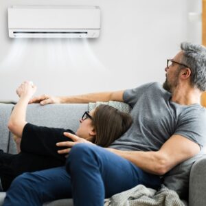 A couple sitting on the couch and turning on their air conditioner