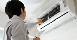 AC unit technician pointing to a wall-mounted AC unit